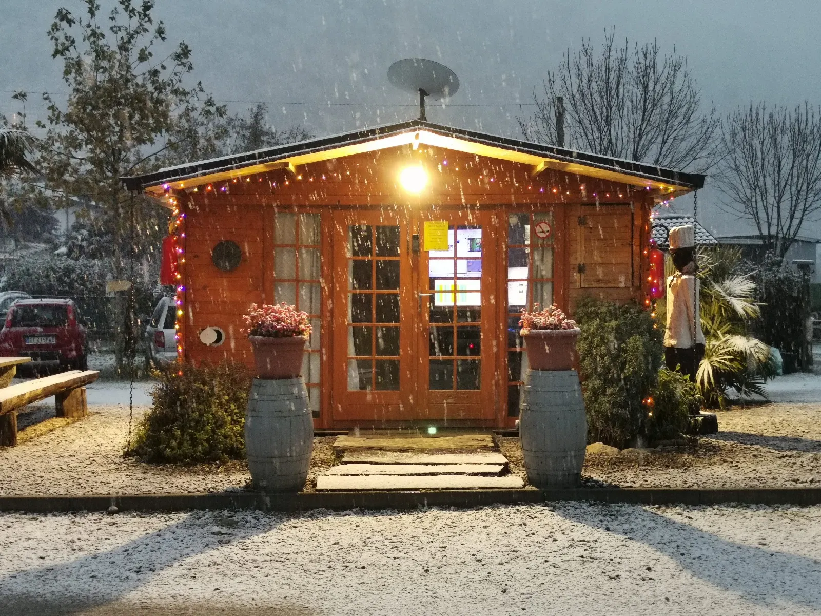 Das beleuchtete Holzhäuschen während eines abendlichen Schneefalls
