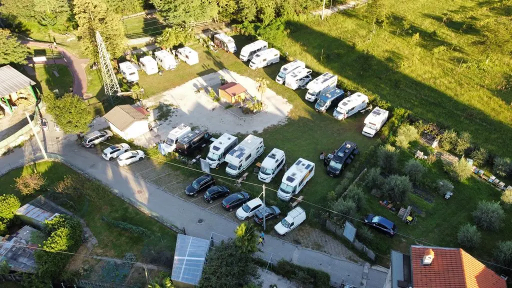 Luftaufnahme des Parkplatzes mit zahlreichen Wohnmobilen und Autos in Reihe