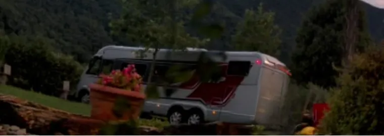 Ein Wohnmobil in der Dämmerung, umgeben von Grün und Hügeln