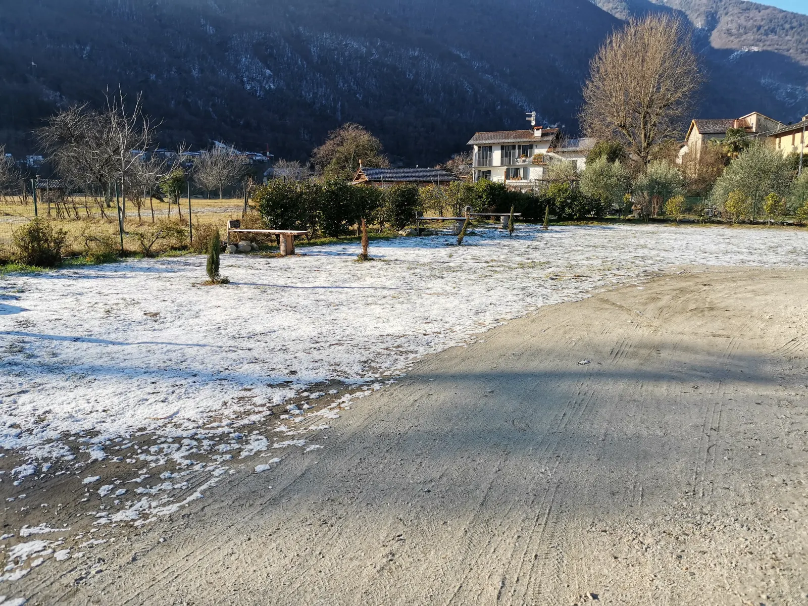 Der Platz mit einer dünnen Schneeschicht, die Zufahrt geräumt, die Berge in der Morgensonne
