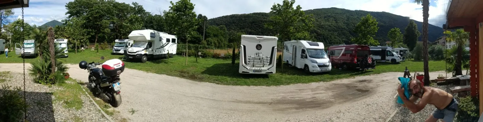 Panoramablick auf den Parkplatz mit Wohnmobilen auf der Wiese und den Bergen im Hintergrund